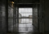 Cancello interno di un istituto penitenziario con area esterna visibile oltre le sbarre