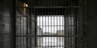 Cancello interno di un istituto penitenziario con area esterna visibile oltre le sbarre